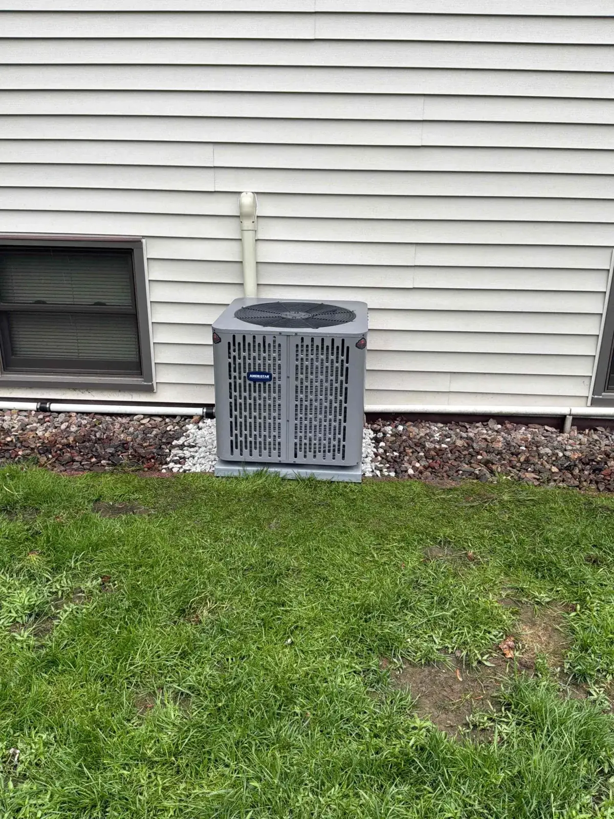 After — new Ameristar condenser set on a stone bed with the line set run tight to the wall