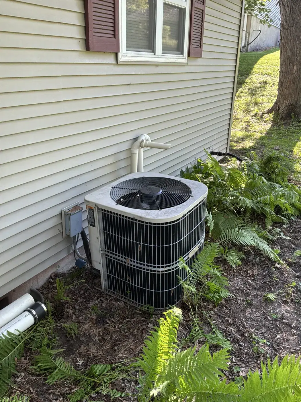 Before — aging outdoor unit sitting tight against the house