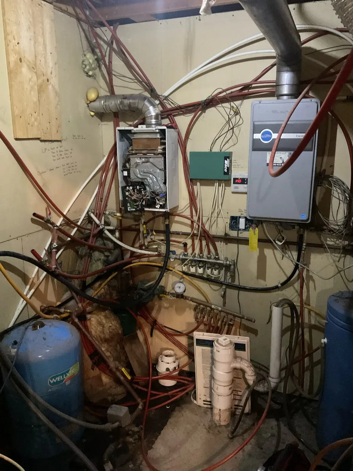 Before — the old micro-boiler with an open panel, tangled PEX and no real layout to the system