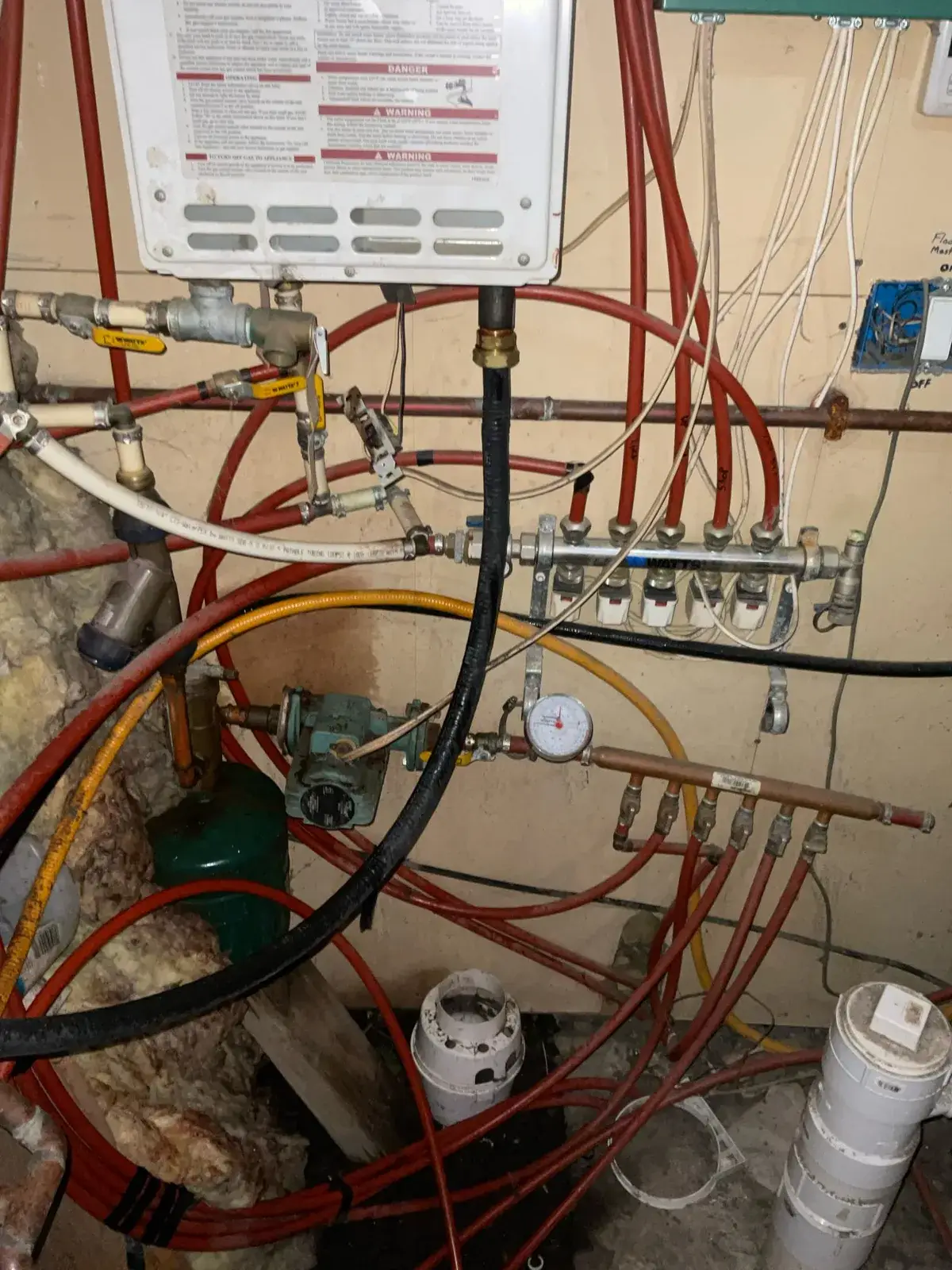 Before — the original manifold and circulator, PEX bundled with no isolation or labeling