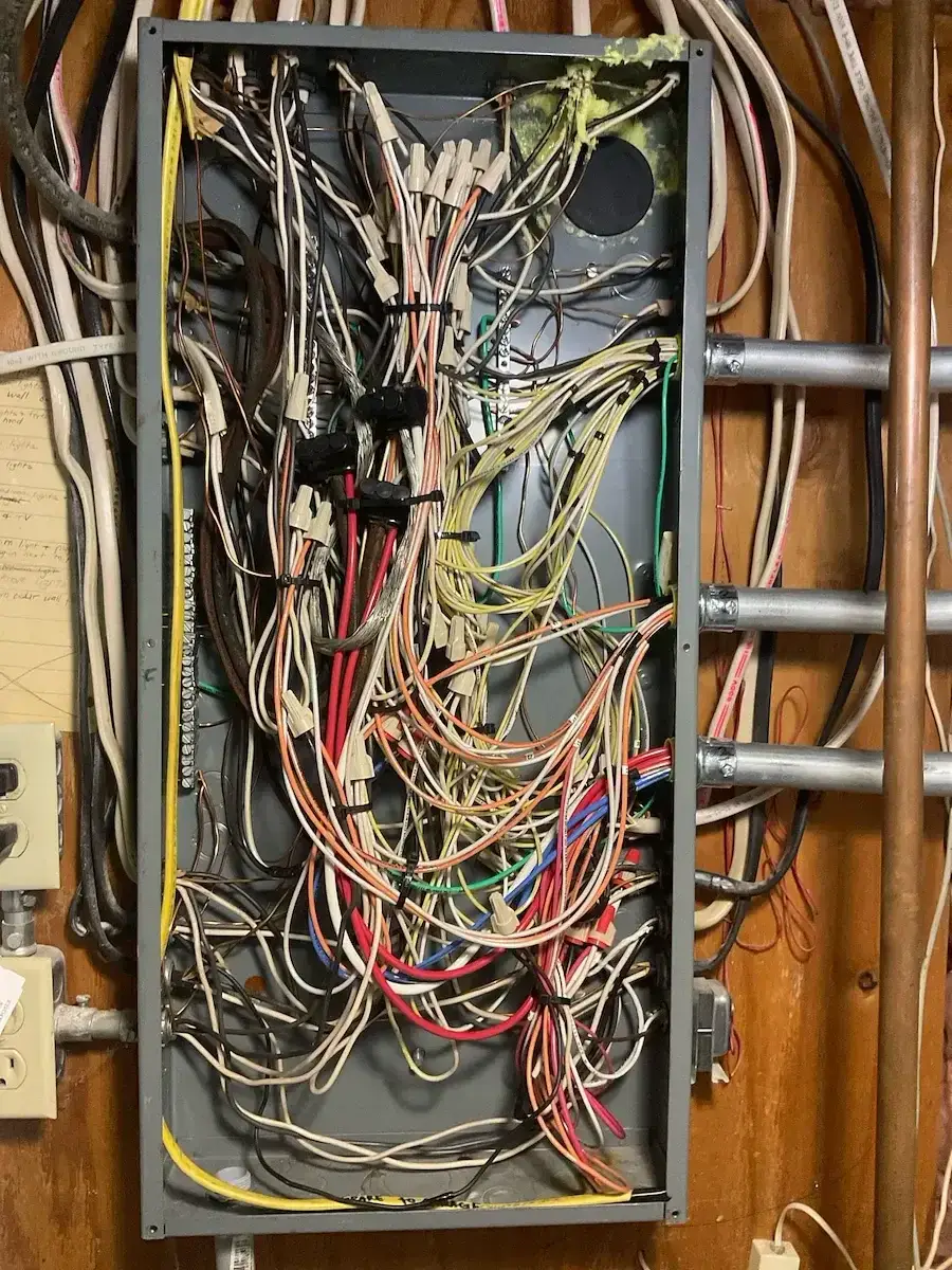 Old service panel de-energized and converted to a junction box — all existing circuits spliced and made safe before the new panel was set