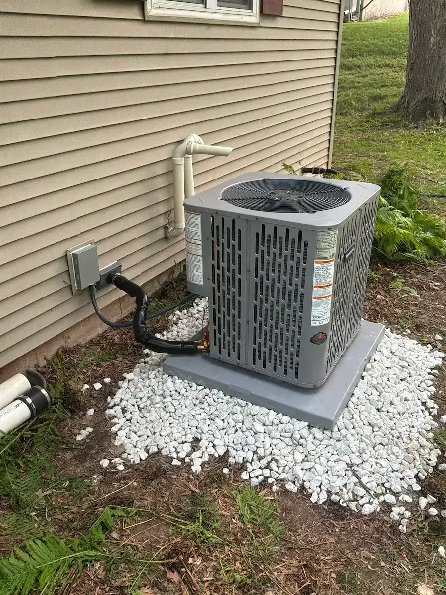 After — new condenser set on a fresh pad and stone bed with a new disconnect