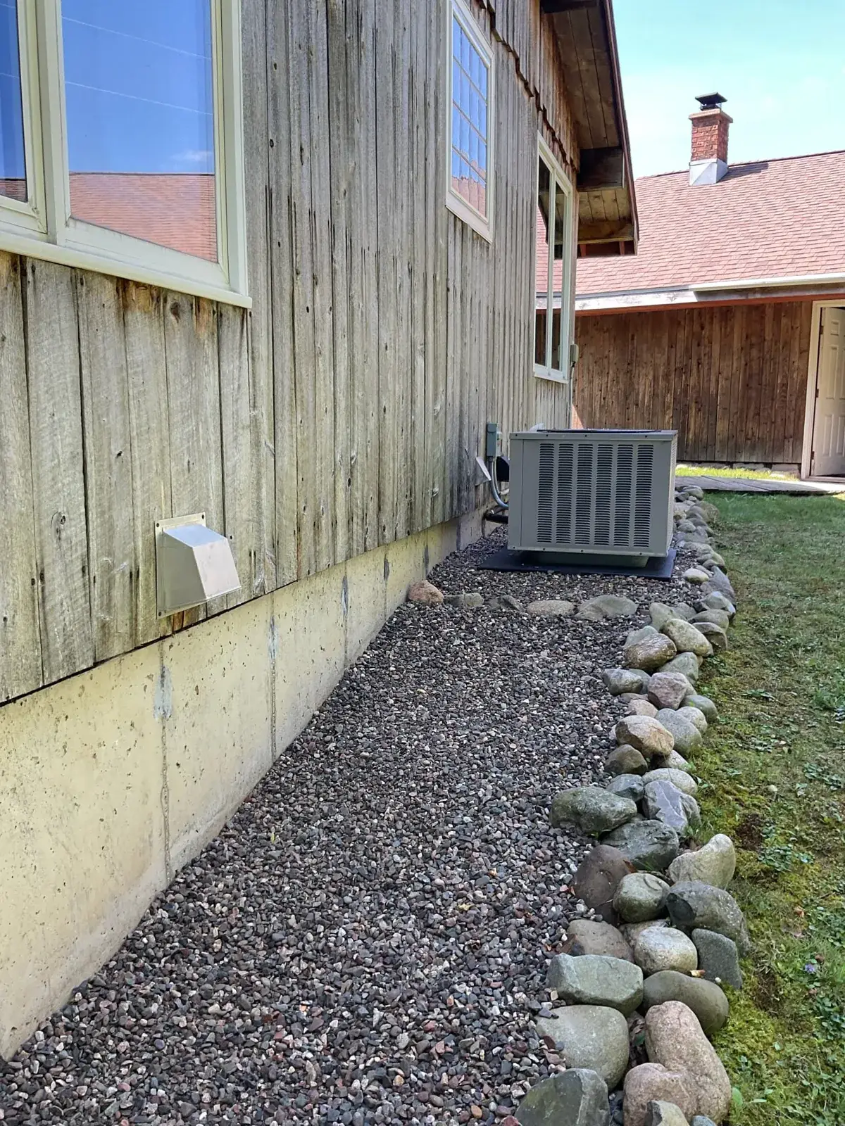 New condenser tucked along the house on a fresh stone bed