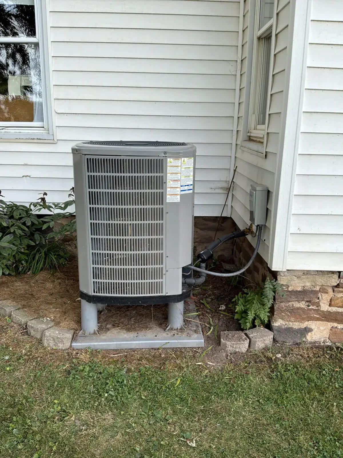 New condenser set on risers with the line set and disconnect run clean to the wall