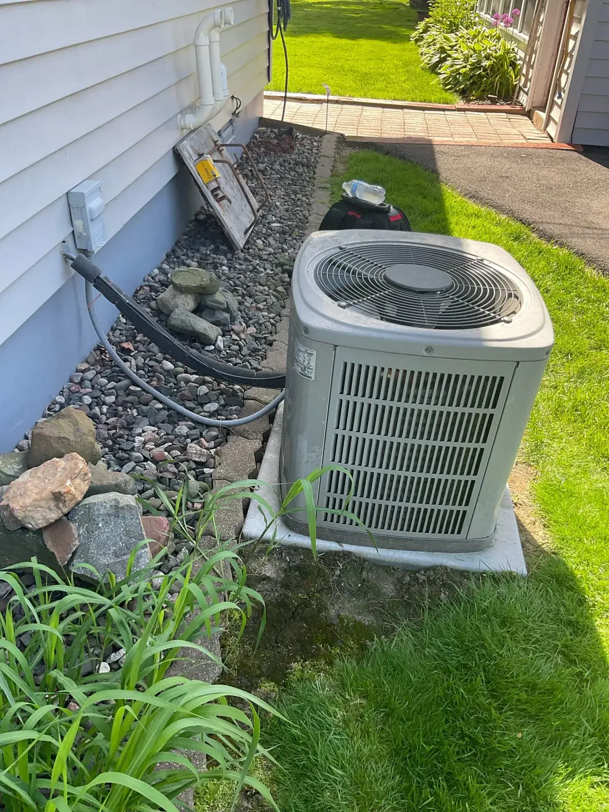 Before — the old outdoor unit crowded by landscaping and rock