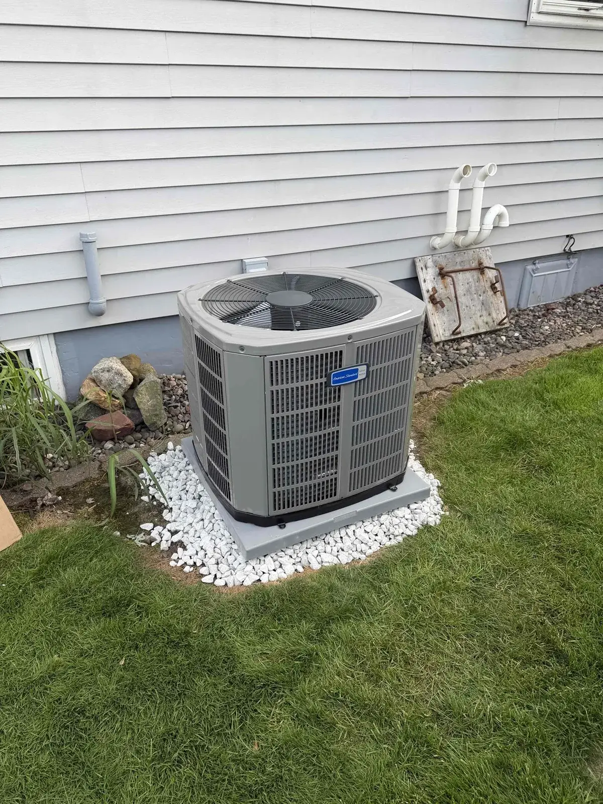 After — new American Standard condenser on a stone bed, clear of the landscaping
