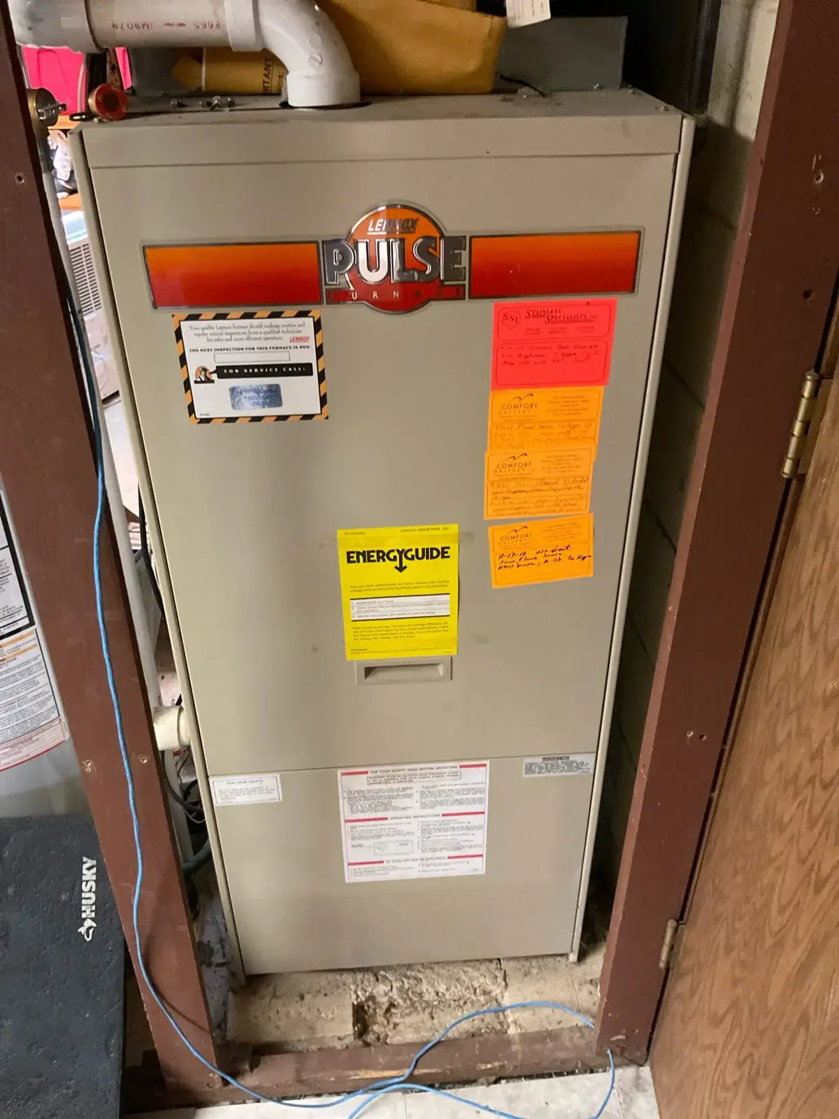 Before — an original Lennox Pulse furnace in a hallway closet, red-tagged and done